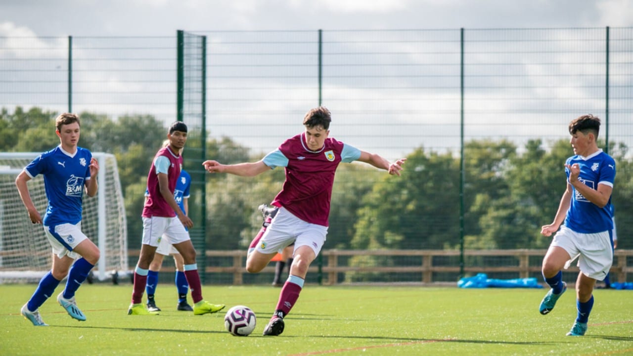 young man in his burnley fc kit kicking a ball